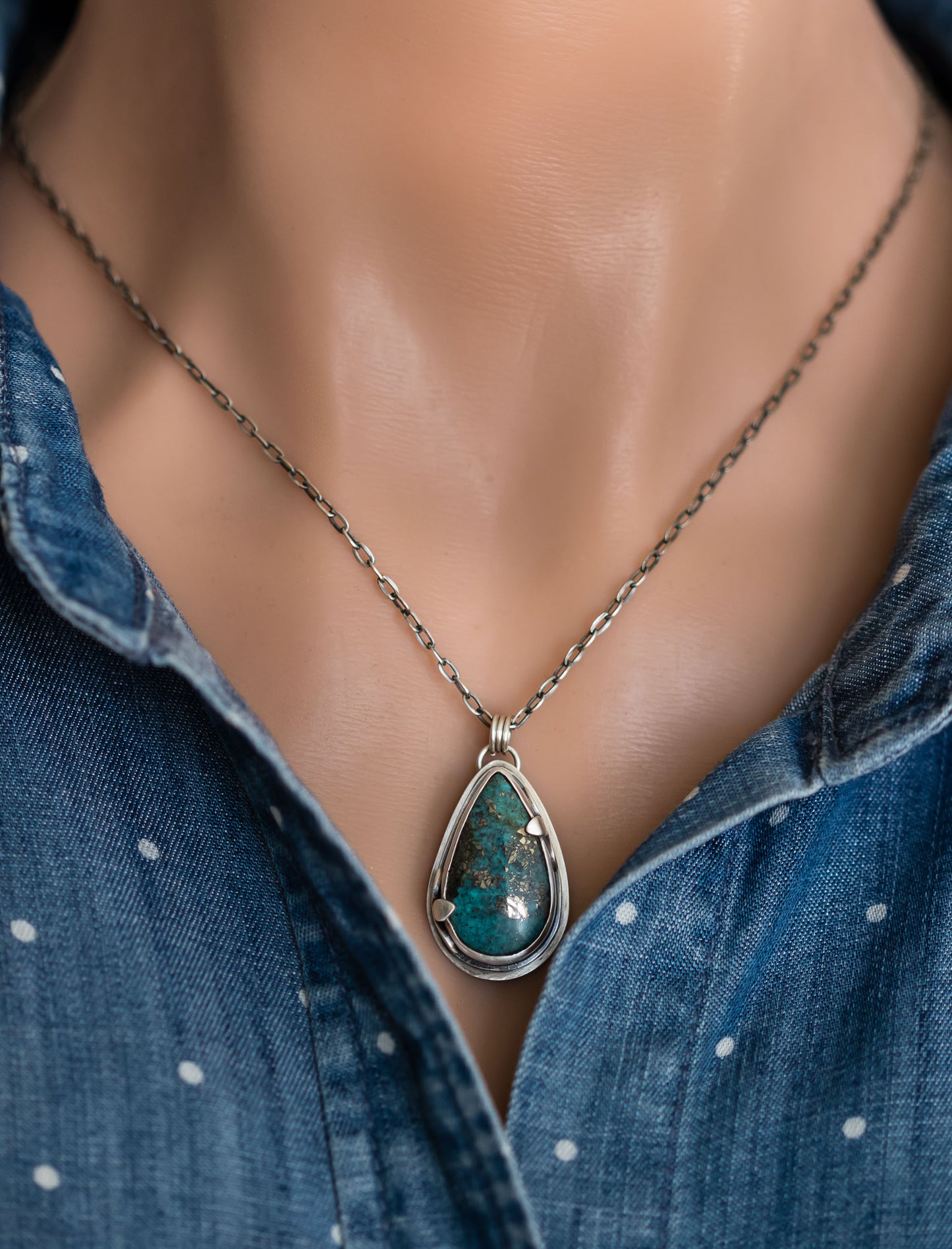 Handmade sterling silver Morenci 2 turquoise teardrop necklace worn on a model, styled with a blue polka dot denim shirt, highlighting the pendant's boho aesthetic.