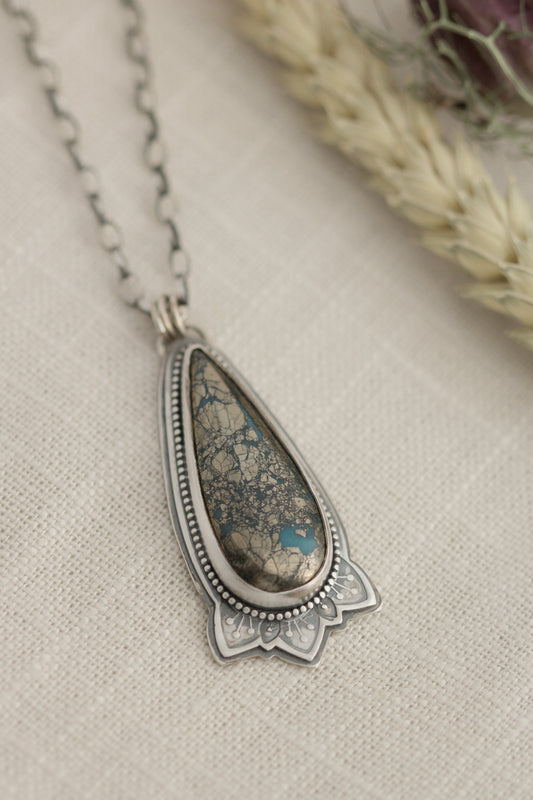 Morenci 2 sterling silver necklace with a 2" turquoise pendant on a light fabric background with dried flowers.