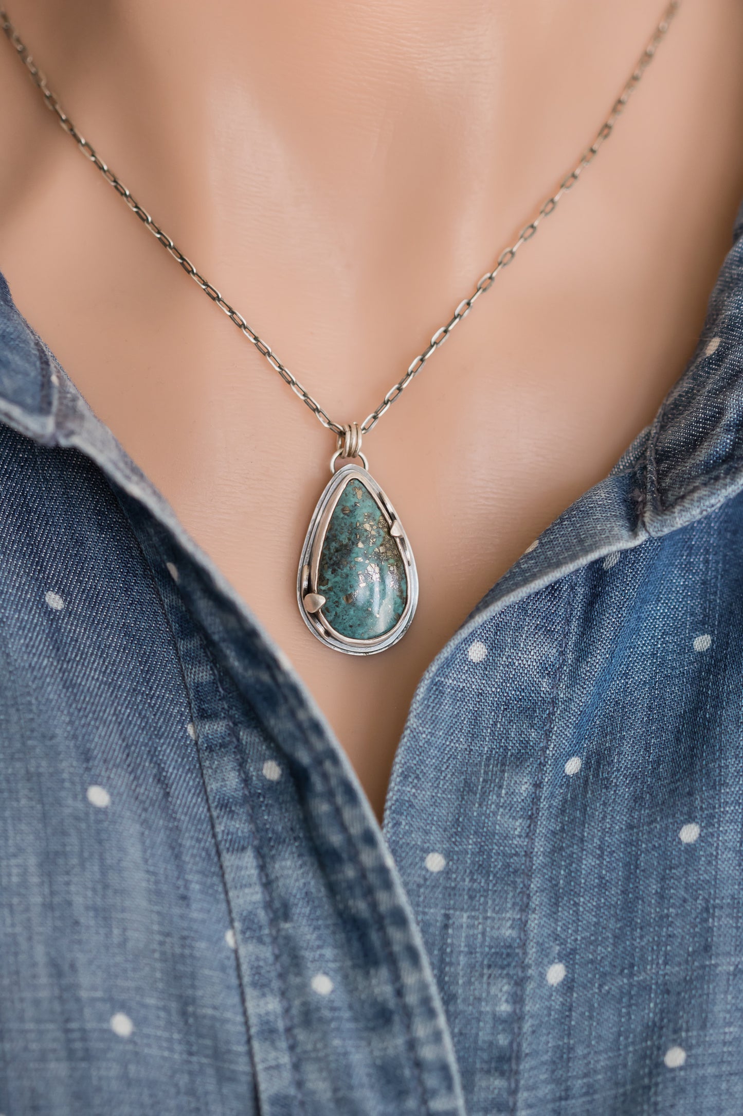 Handmade sterling silver Morenci 2 turquoise teardrop necklace worn on a model, styled with a blue polka dot denim shirt, highlighting the pendant's boho aesthetic.