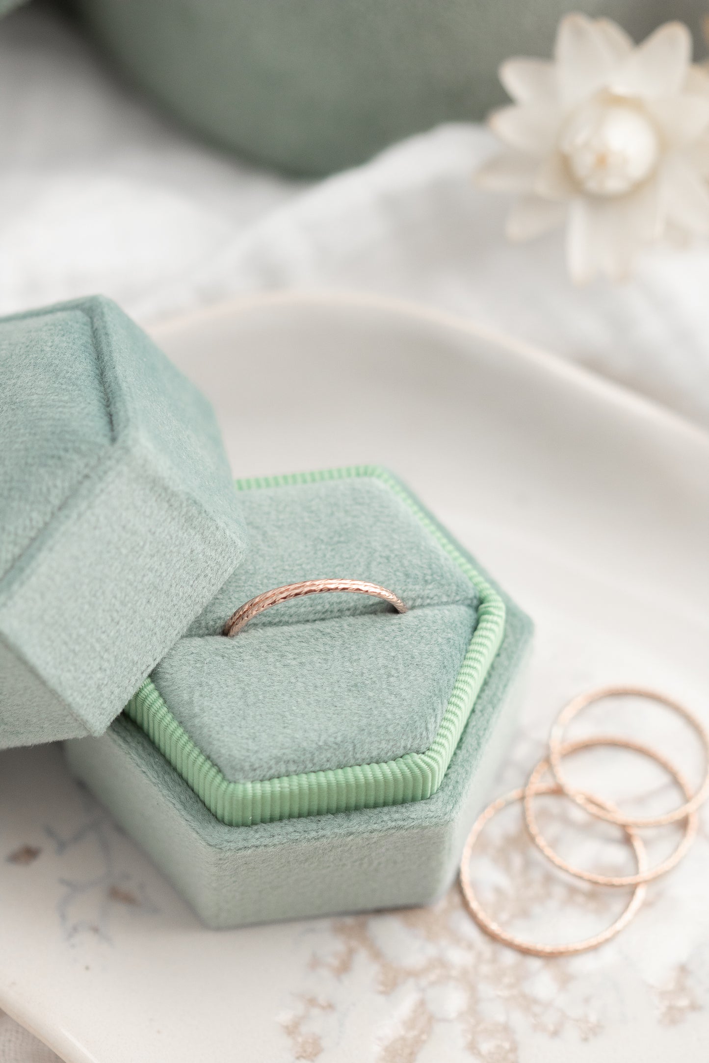 Green hexagonal jewelry box with a ring inside, placed on a light surface.