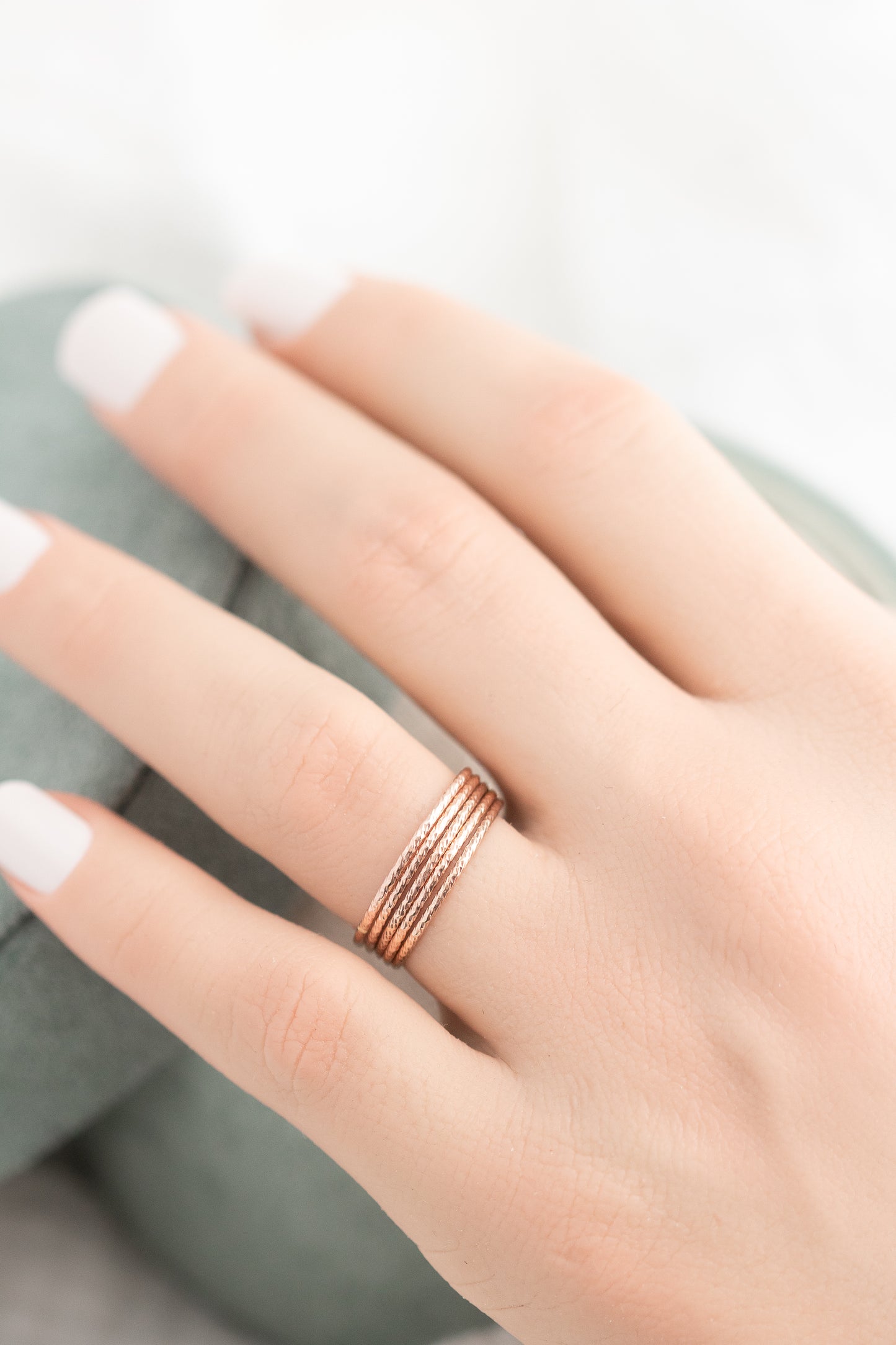 Rose gold ring on a person's finger with a blurred background