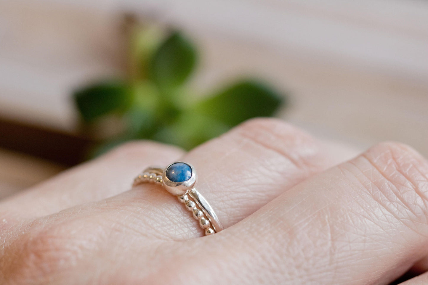 Hand wearing a denim lapis and beaded silver ring set, highlighting unique handmade design.