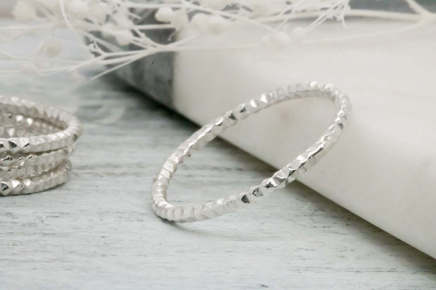 Sterling silver diamond cut ring on rustic wood, 1.5mm wide, sparkling faceted texture, stackable.