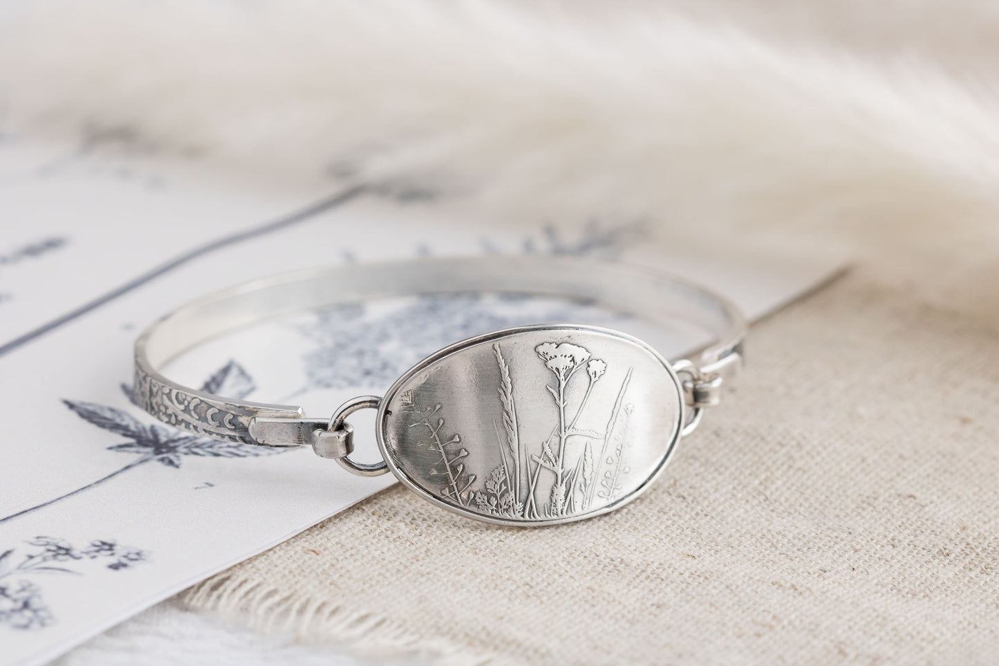 Handmade sterling silver wildflower tension cuff bracelet, crafted in Soldotna, Alaska, featuring a textured band and floral design.
