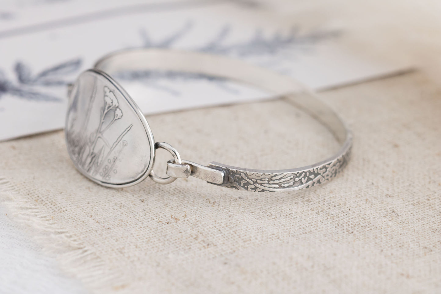 Handmade sterling silver wildflower tension cuff bracelet, crafted in Soldotna, Alaska, featuring a textured band and floral design.