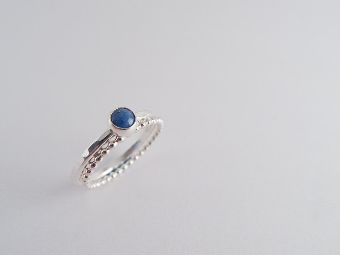 Close-up of a denim lapis ring with a beaded silver band on a white background.