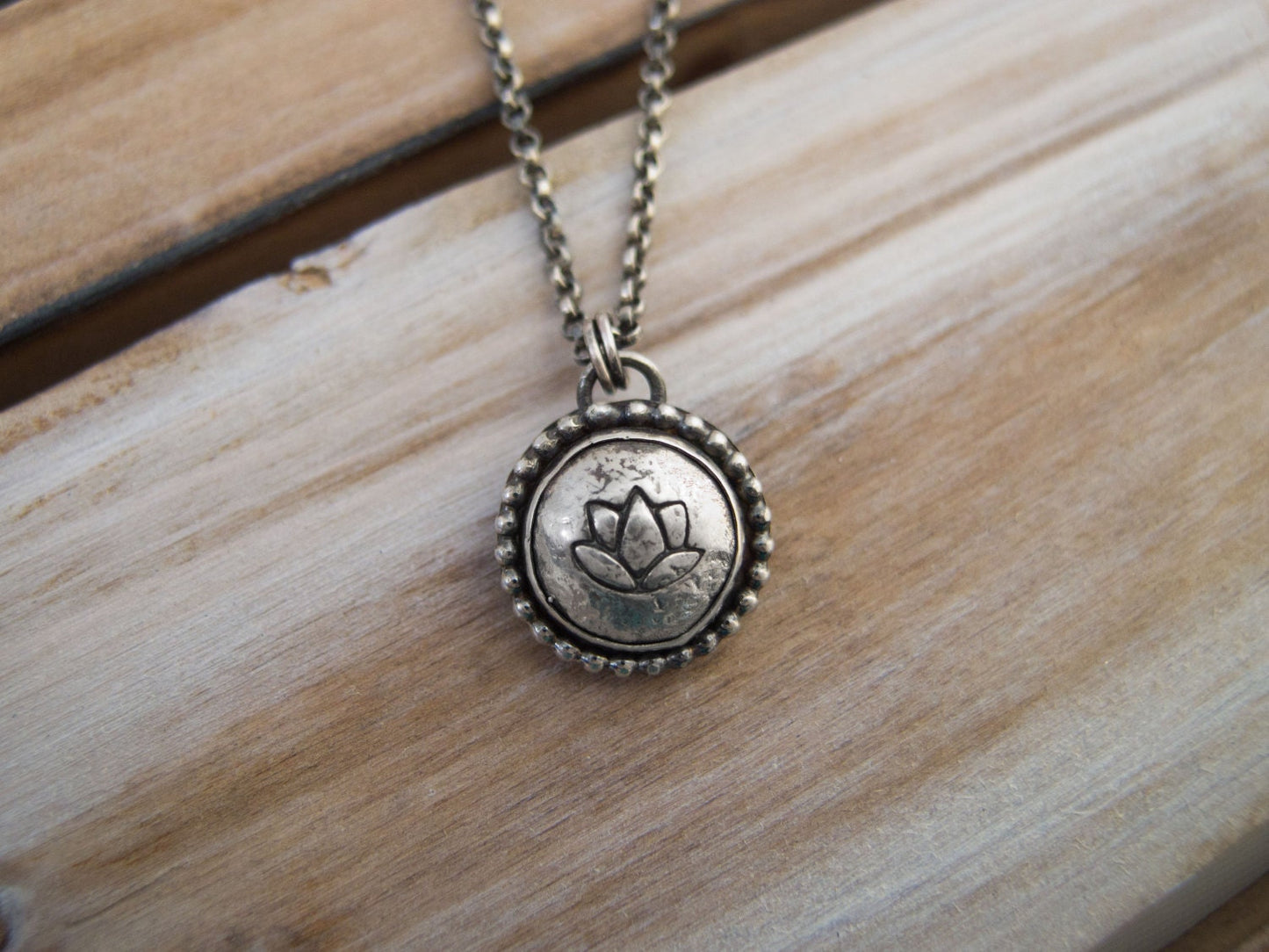 Handcrafted sterling silver lotus flower yoga necklace with a 16"-20" chain, displayed on a wooden surface, ideal for gifting.
