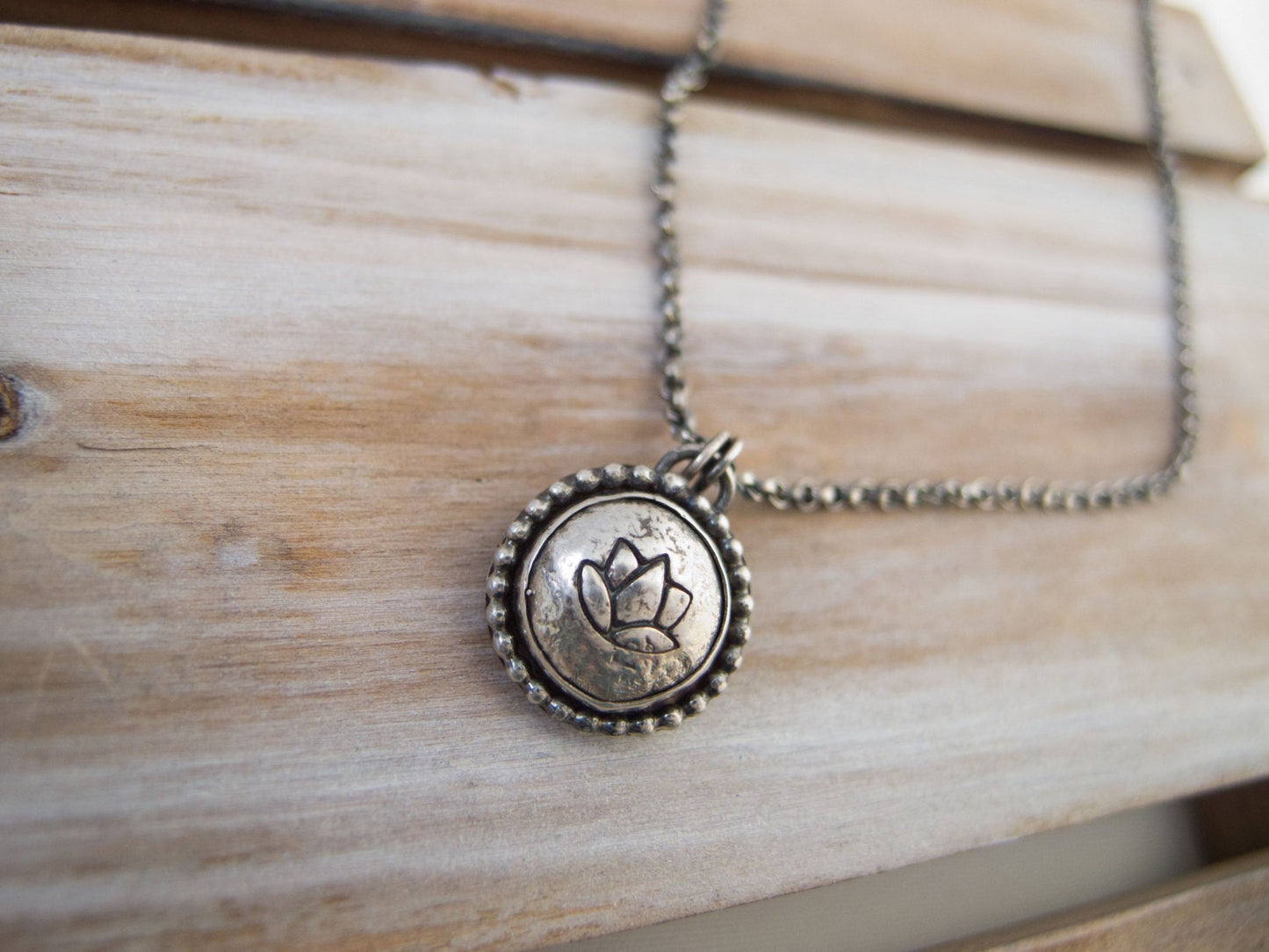 Handcrafted sterling silver lotus flower yoga necklace with a 16"-20" chain, displayed on a wooden surface, ideal for gifting.