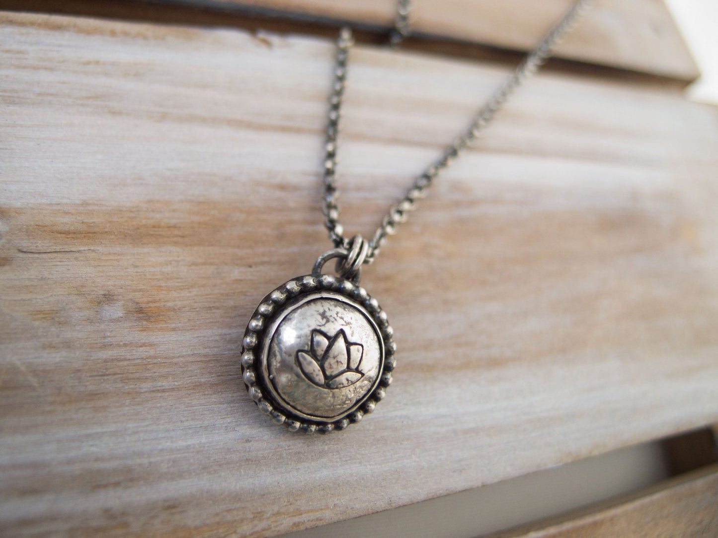 Handcrafted sterling silver lotus flower yoga necklace with a 16"-20" chain, displayed on a wooden surface, ideal for gifting.