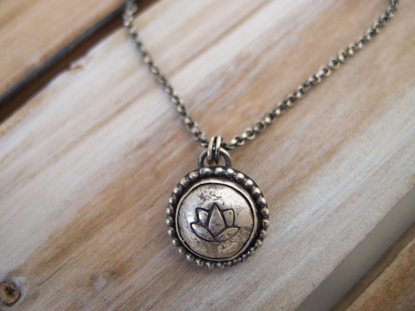 Handcrafted sterling silver lotus flower yoga necklace with a 16"-20" chain, displayed on a wooden surface, ideal for gifting.