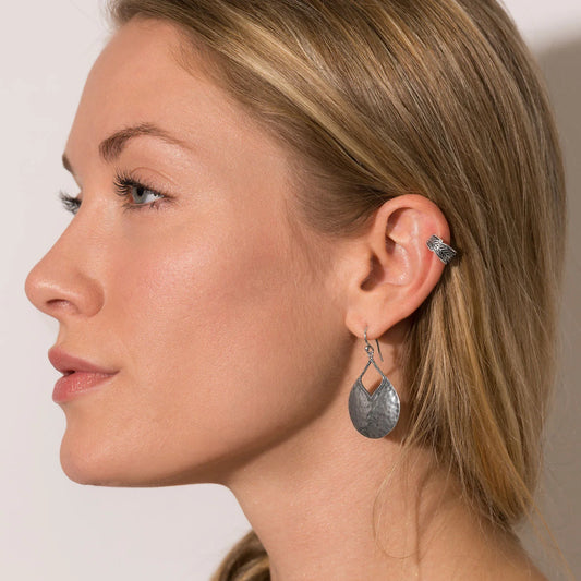 Close-up of a woman wearing silver earrings with a neutral background