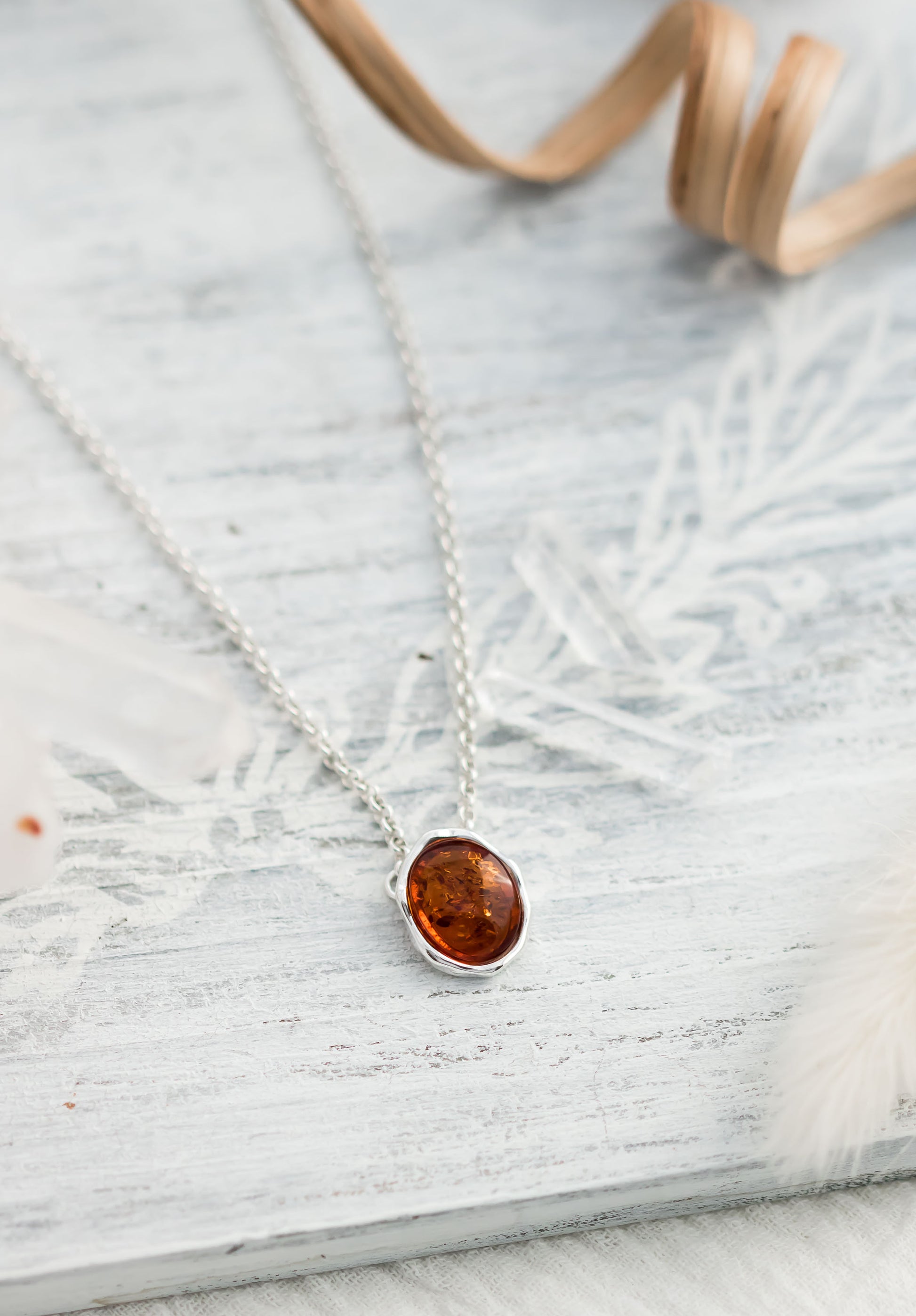 Baltic Amber oval cabochon pendant in a hammered sterling silver bezel setting on a sterling silver rolo chain.