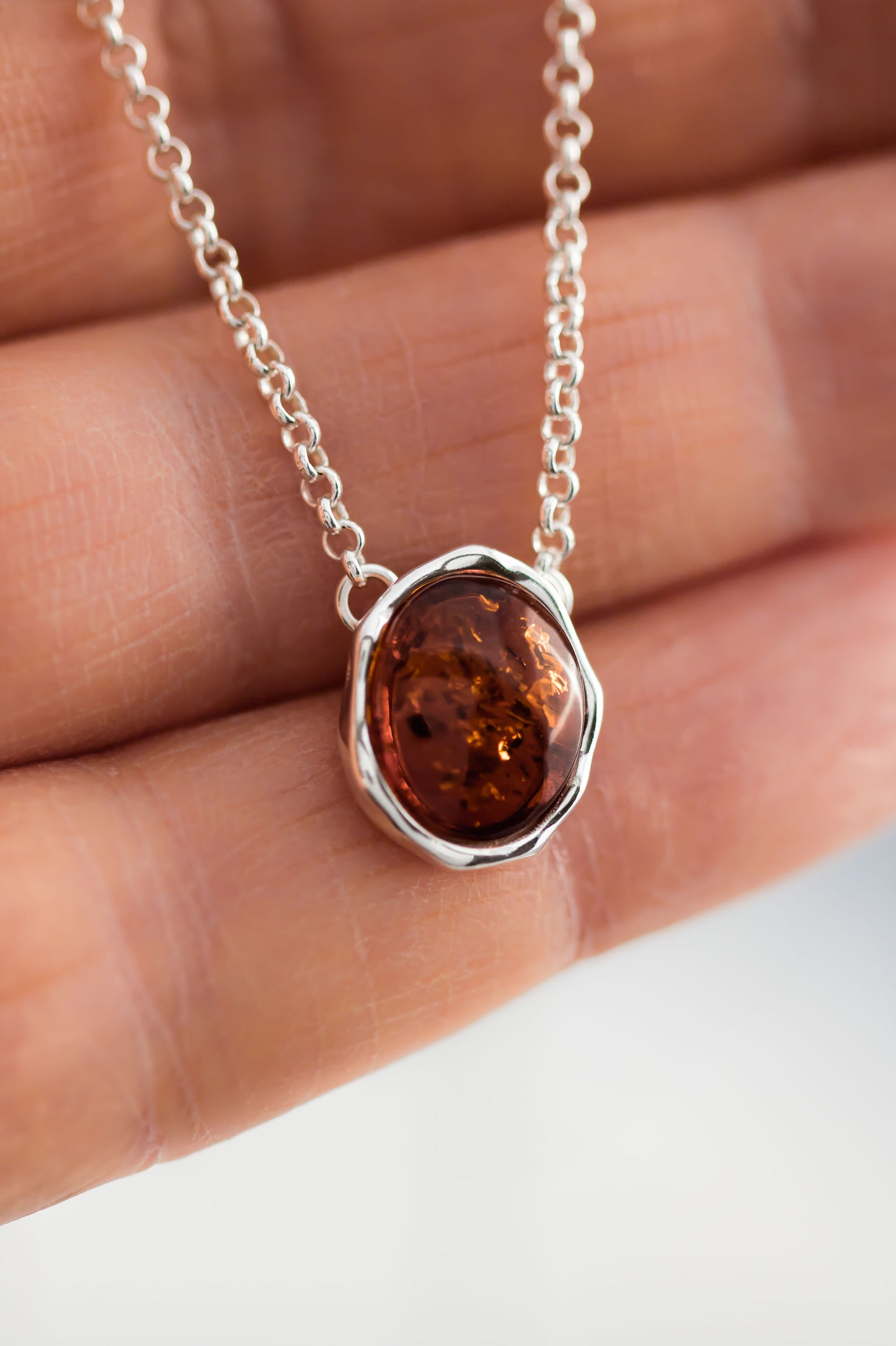 Baltic Amber oval cabochon pendant in a hammered sterling silver bezel setting on a sterling silver 18 inch with 2 inch extender rolo chain.