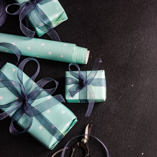 Gift boxes wrapped in green paper with ribbons on a black surface