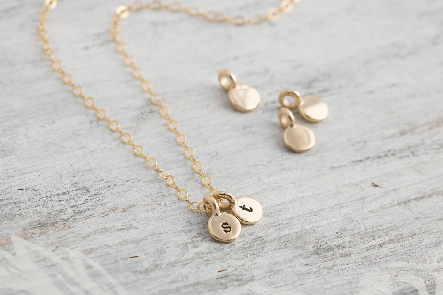 solid 14k tiny round initial charm on a solid 14k gold chain.