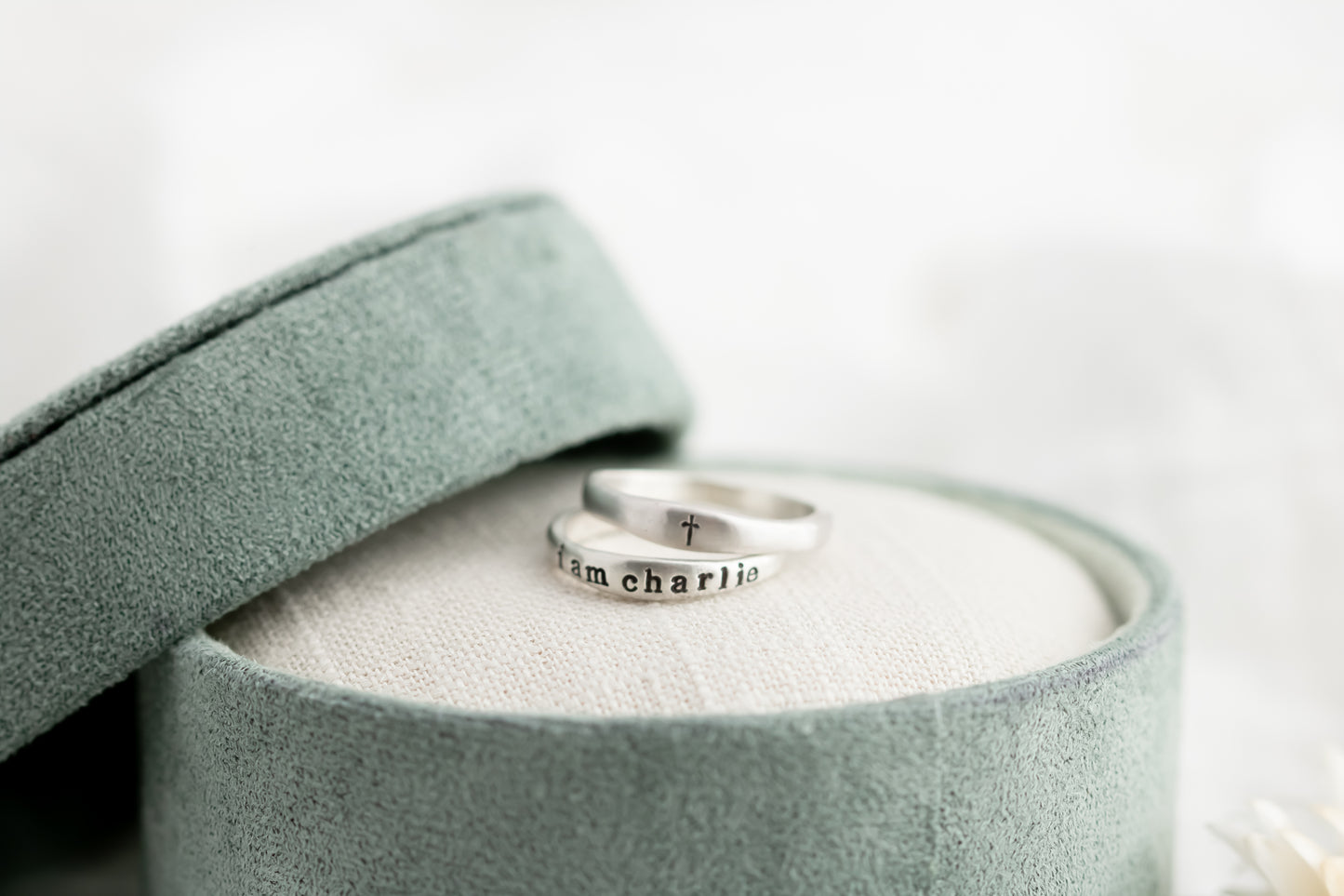 Silver ring with engraving in a green jewelry box on a light background