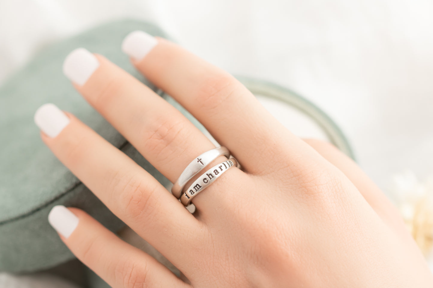 Hand wearing multiple silver rings with a blurred background