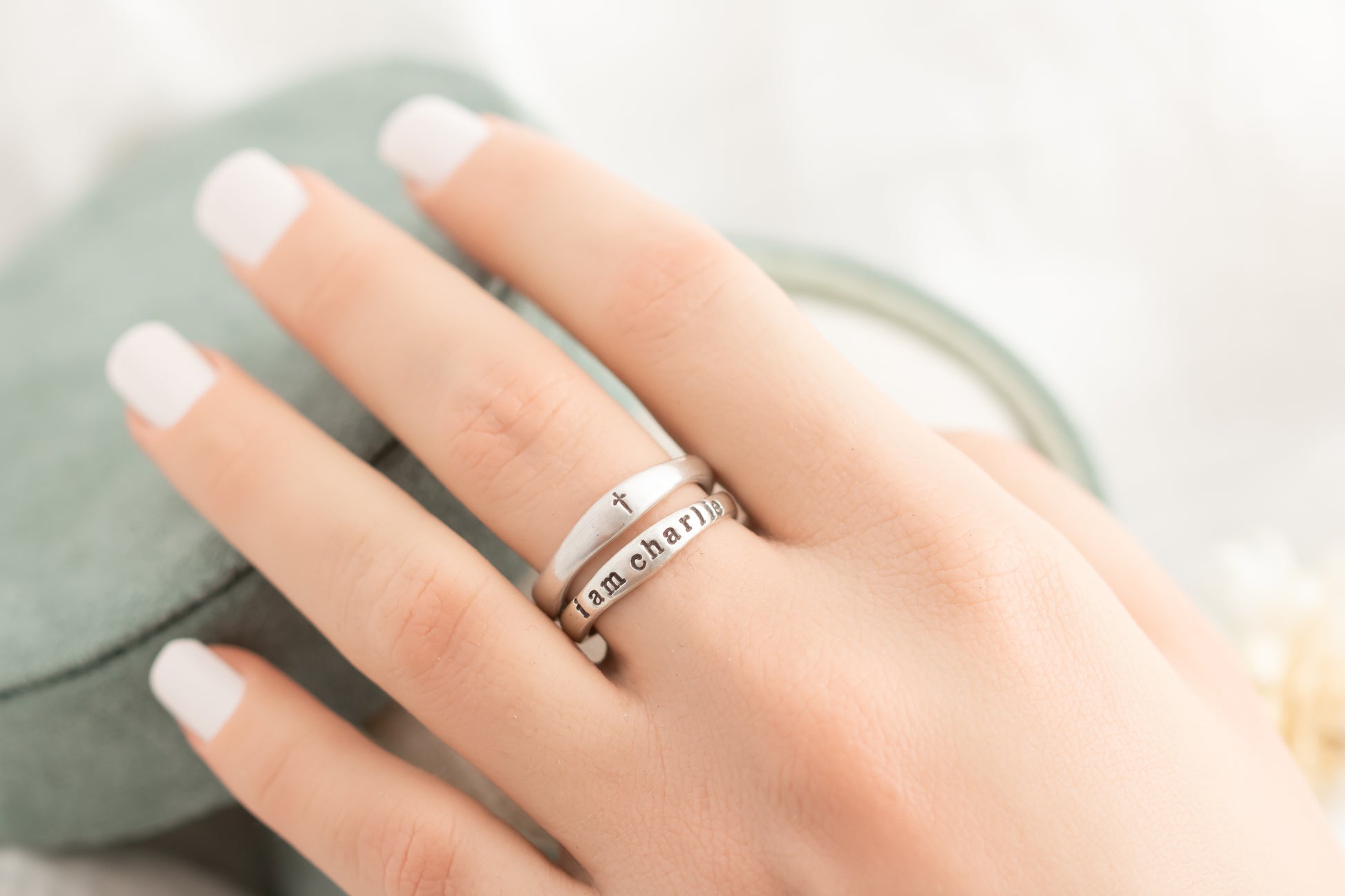 Hand wearing multiple silver rings with a blurred background