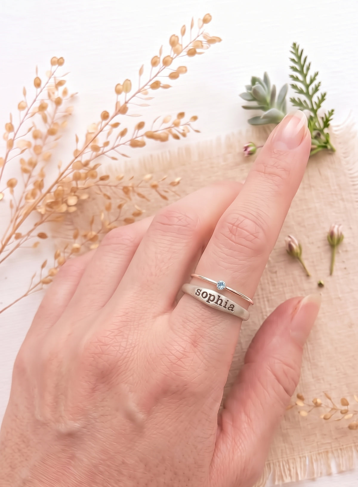Sterling silver ring with the name Sophia and a sterling silver birthstone ring on a models finger.