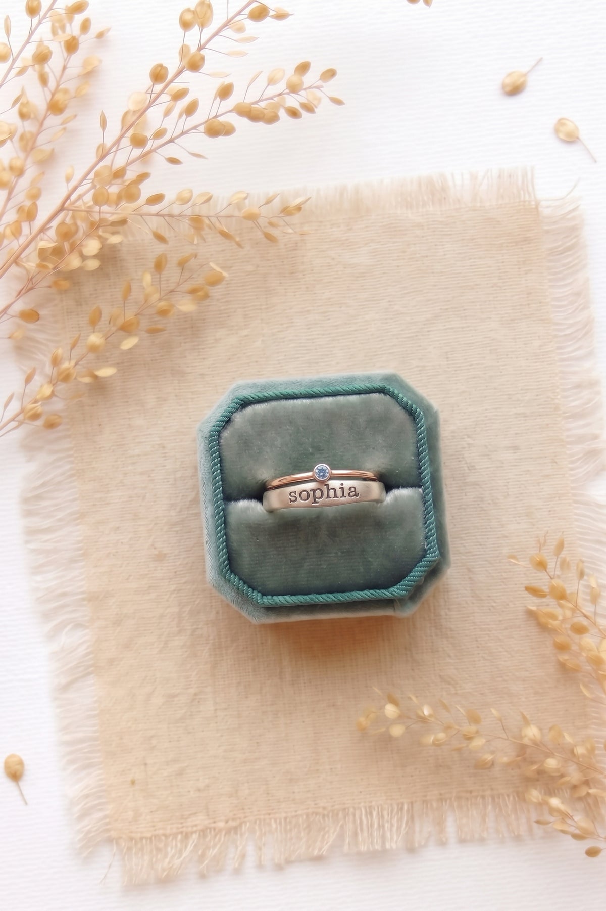Sterling silver ring with the name Sophia and a sterling silver birthstone ring in a teal velvet ring box.