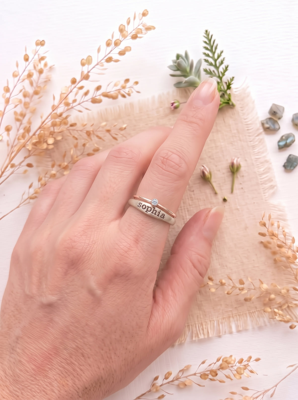 Sterling silver ring with the name Sophia and a sterling silver birthstone ring on a models finger.