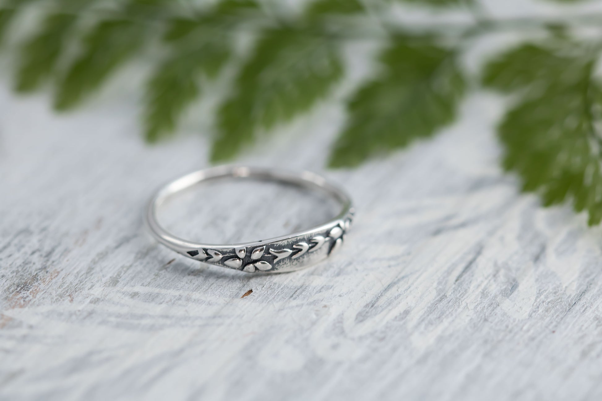 Narrow sterling silver ring with wildflower tapestry impression. 