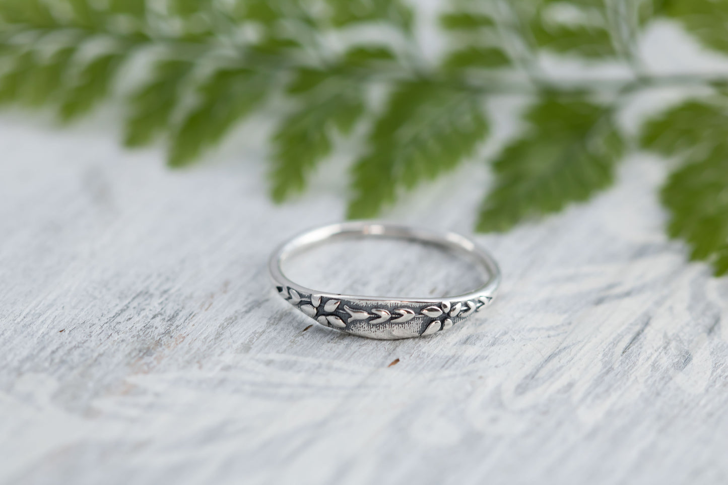 Narrow sterling silver ring with wildflower tapestry impression. 