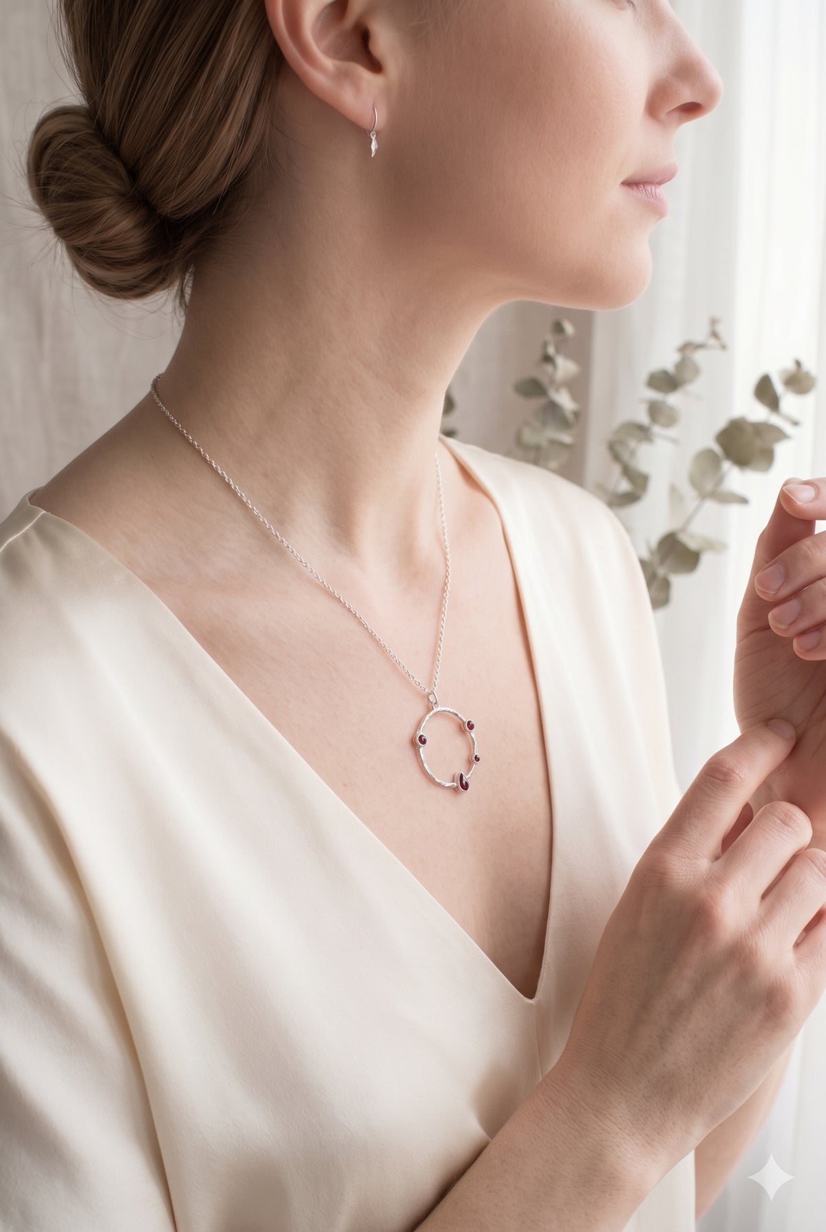 Model wearing a sterling silver hammered circle necklace with deep red garnet accents against a cream V-neck blouse.