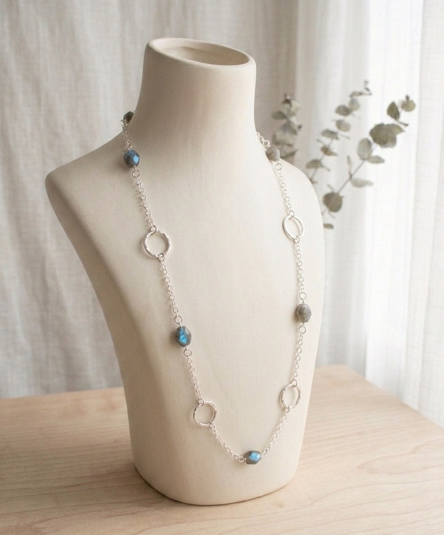 Long 35 inch sterling silver and labradorite necklace with hand made silver circle links and faceted labradorite nuggets on a mannequin bust against a neutral background