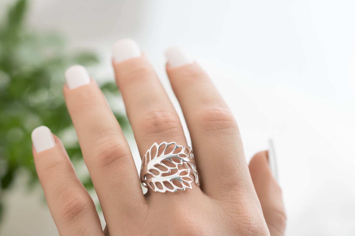 Silver leaf ring on a hand with a blurred background