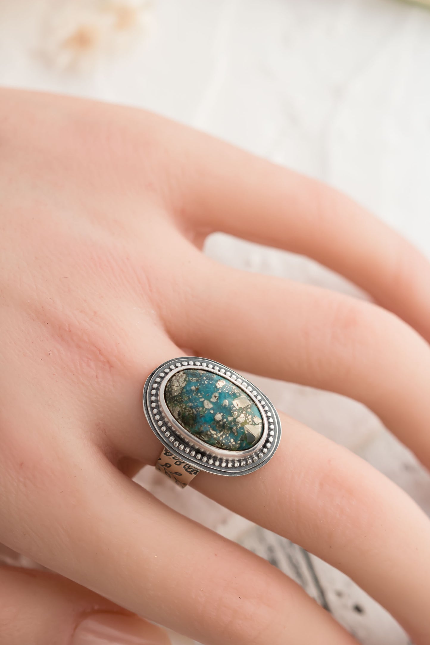 Sterling silver ring with oval morinci #2 Turquoise cabochon in a sterling silver setting surrounded with beaded accent and a floral stamped band.