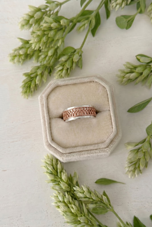 Two-tone ring with a sterling silver hammered band and an outer double crown wire copper band the spins freely in a cream colored velvet ring box. 