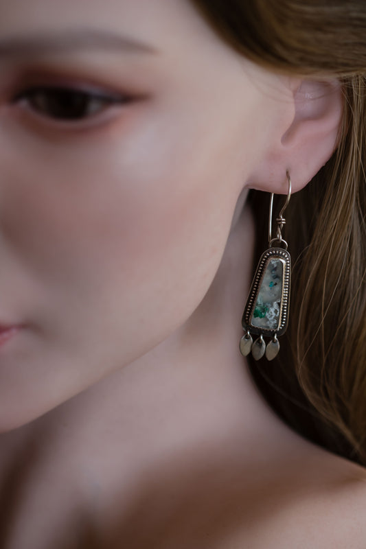 Sterling silver and sugar water flower agate earrings with beaded accent bezel with French hook ear wires on female model.