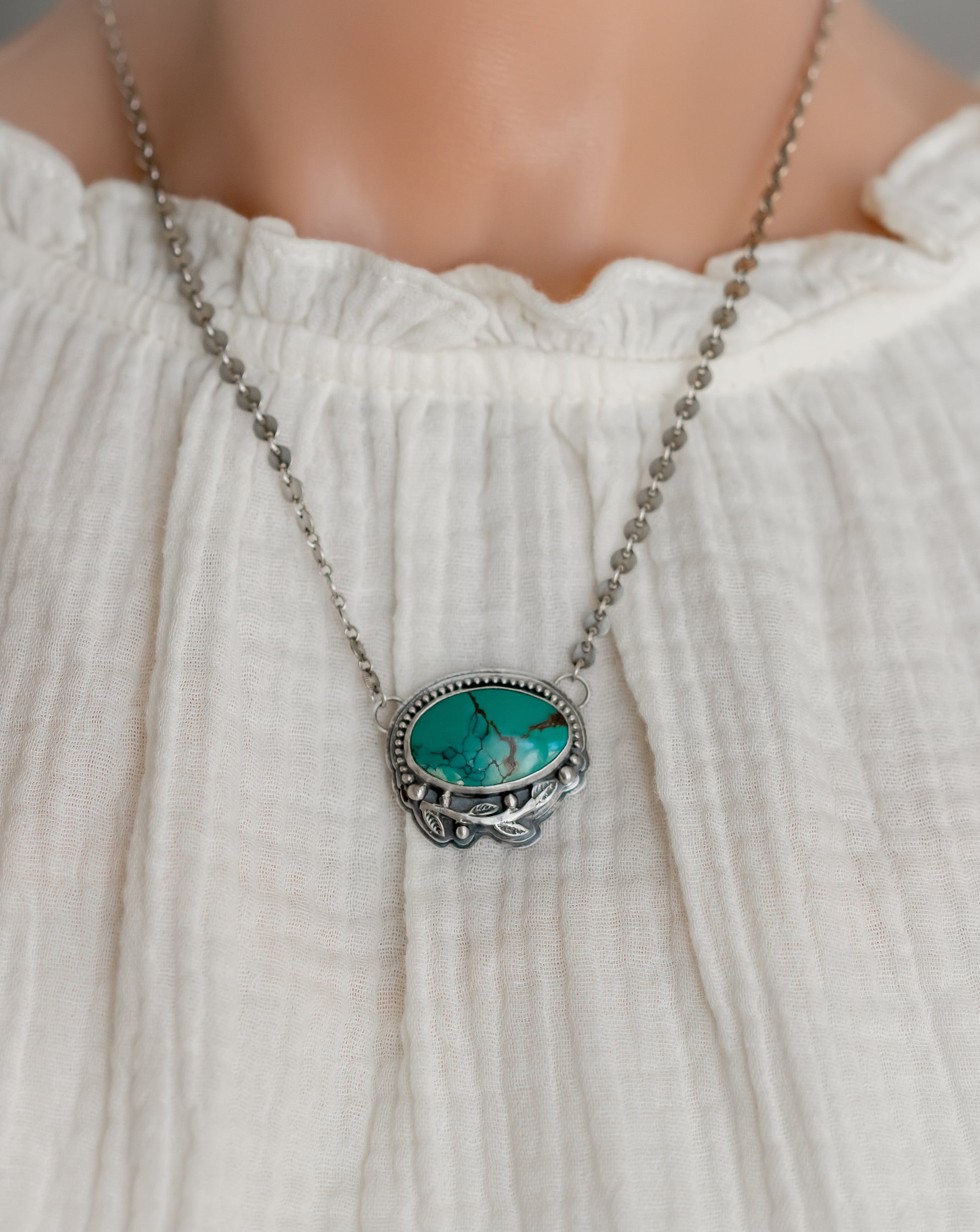 Sterling Silver Turquoise pendant necklace worn on a model with a white top, showcasing bohemian style 
