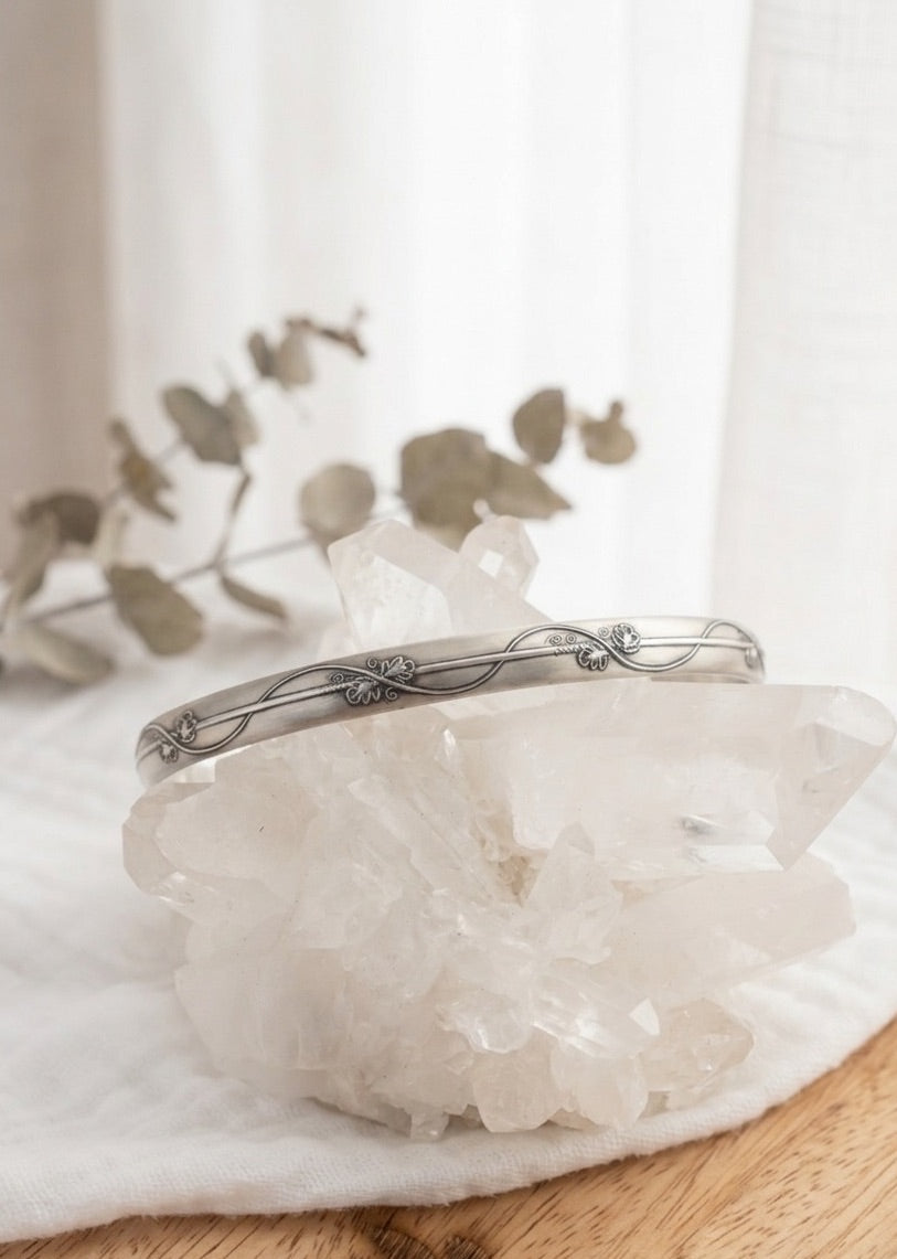Sterling silver bracelet with a floral vine design  on a crystal with a soft background