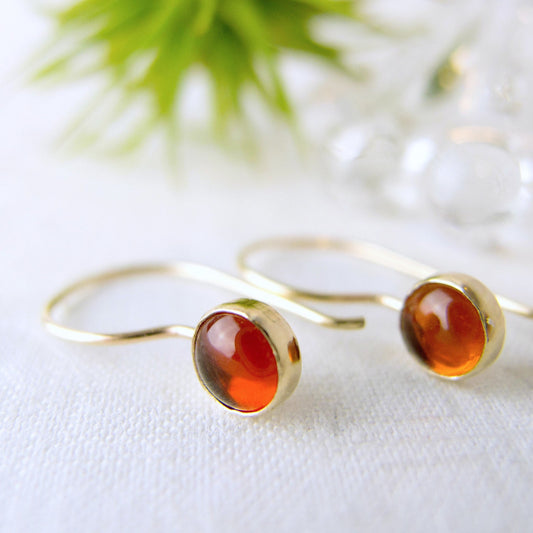 6mm Baltic Amber round cabochon earrings in a solid 14k go bezel with a 14K gold hook wire featuring genuine Baltic amber. 