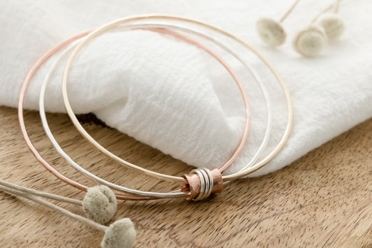 Three mixed metal bangles of sterling silver, 14K gold filled and copper with a copper spinner bead with sterling silver rings.