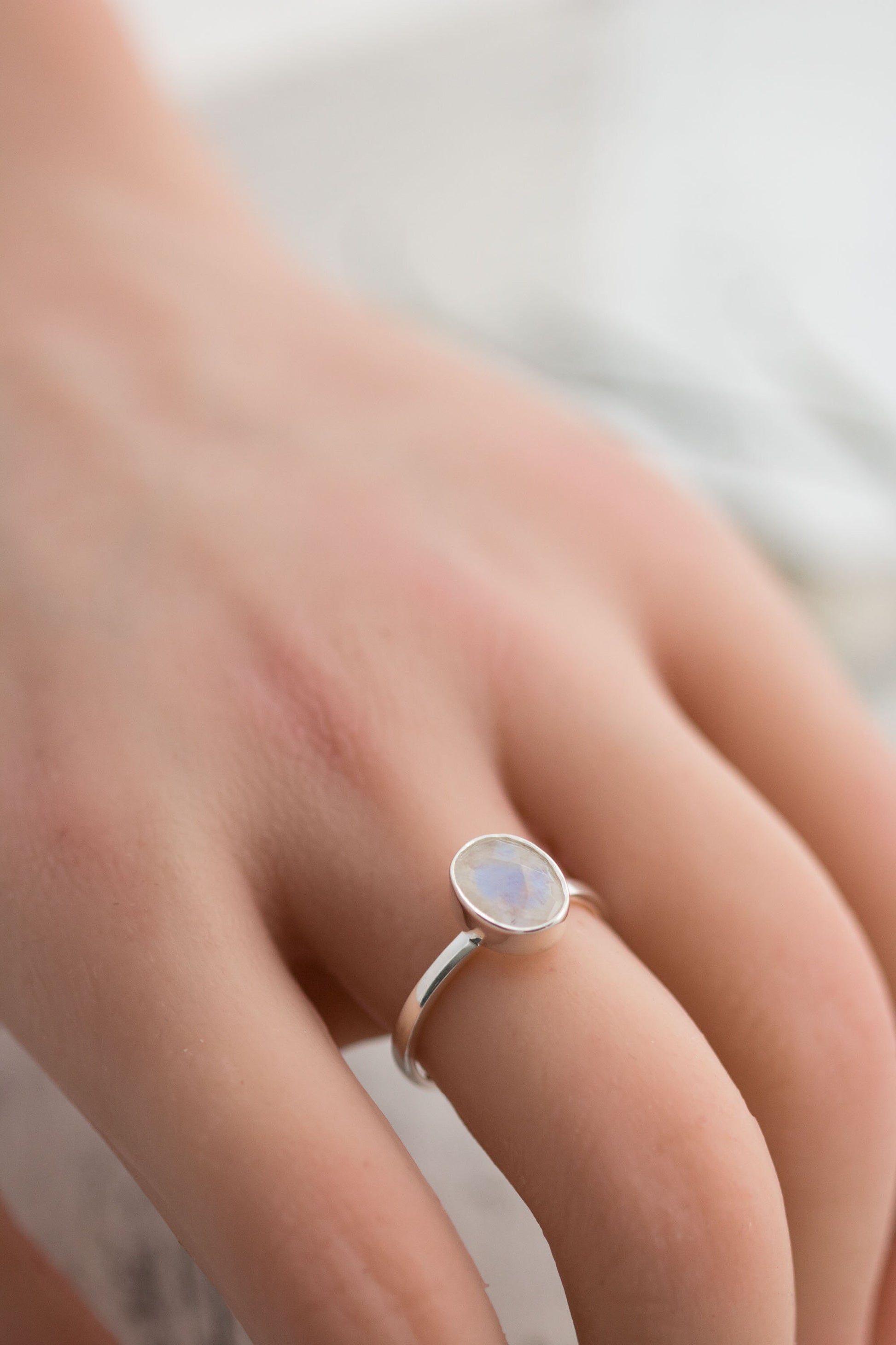 Sterling silver ring with oval faceted moonstone set in a bezel setting with simple silver ring band. 
