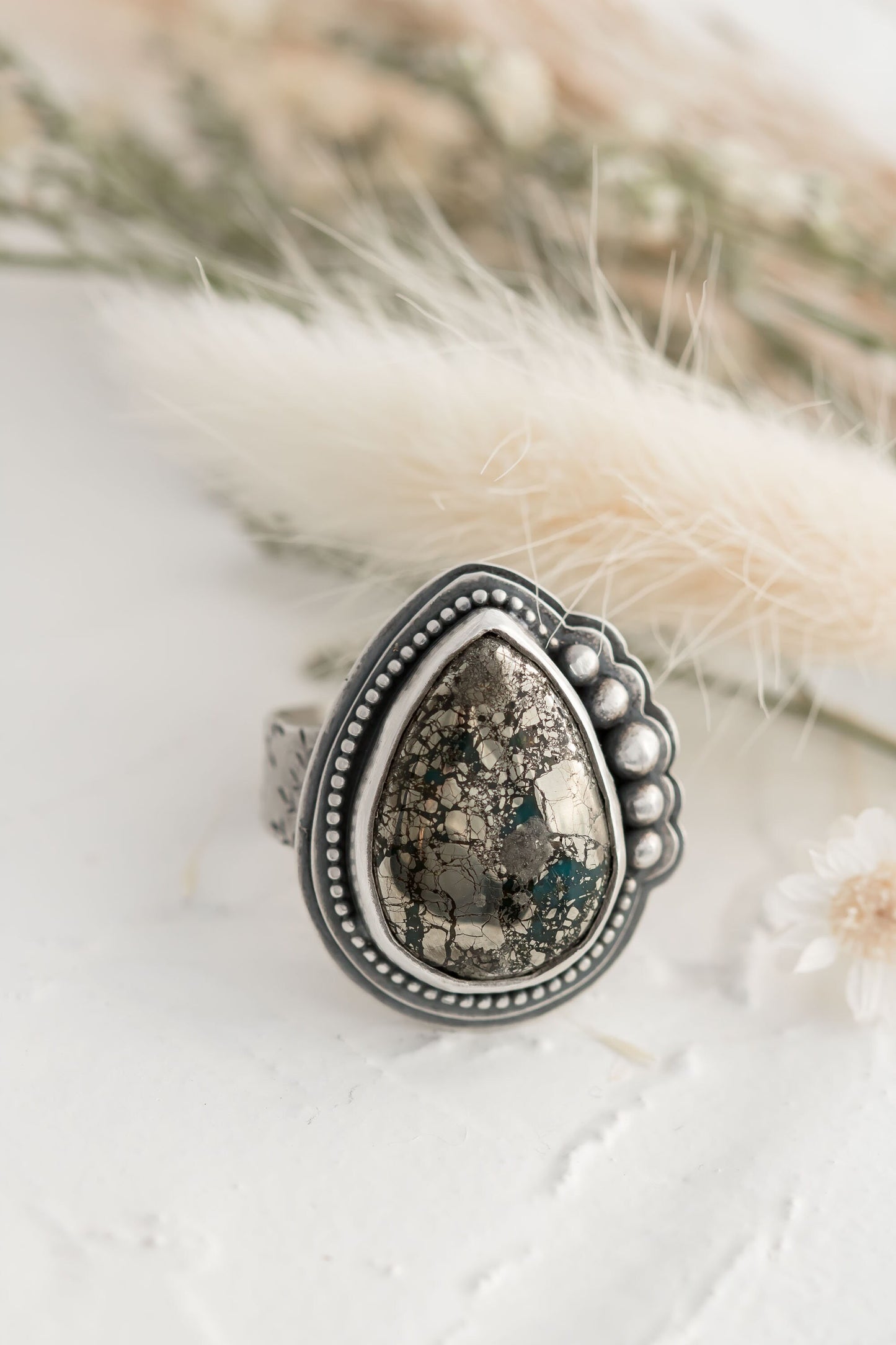 Sterling silver wide band ring will floral design, a morinci 2 turquoise pear shaped cabochon with pyrite inclusions and beaded accent bezel