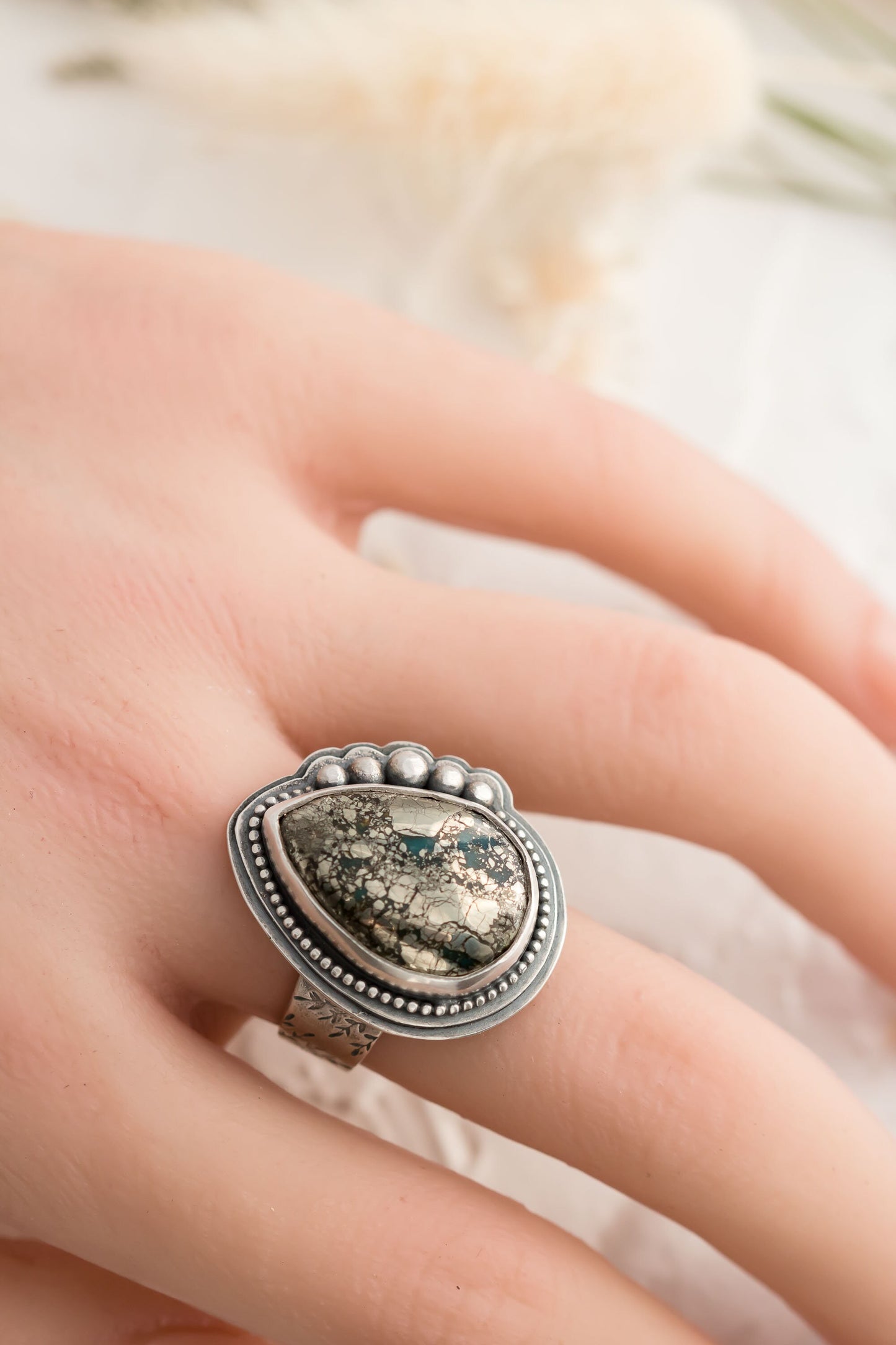 Sterling silver wide band ring will floral design, a morinci 2 turquoise pear shaped cabochon with pyrite inclusions and beaded accent bezel