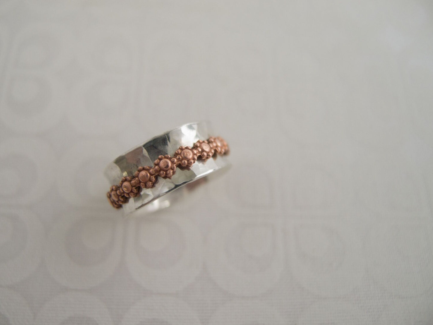 Sterling silver wide hammered ring band with a copper daisy free spinning inner fidget band.