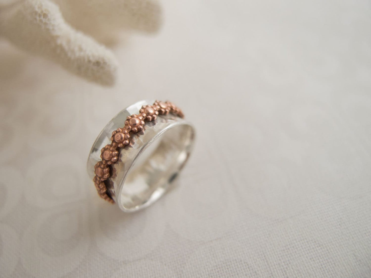 Sterling silver ring band with outer daisy flower copper ring band that spins freely.