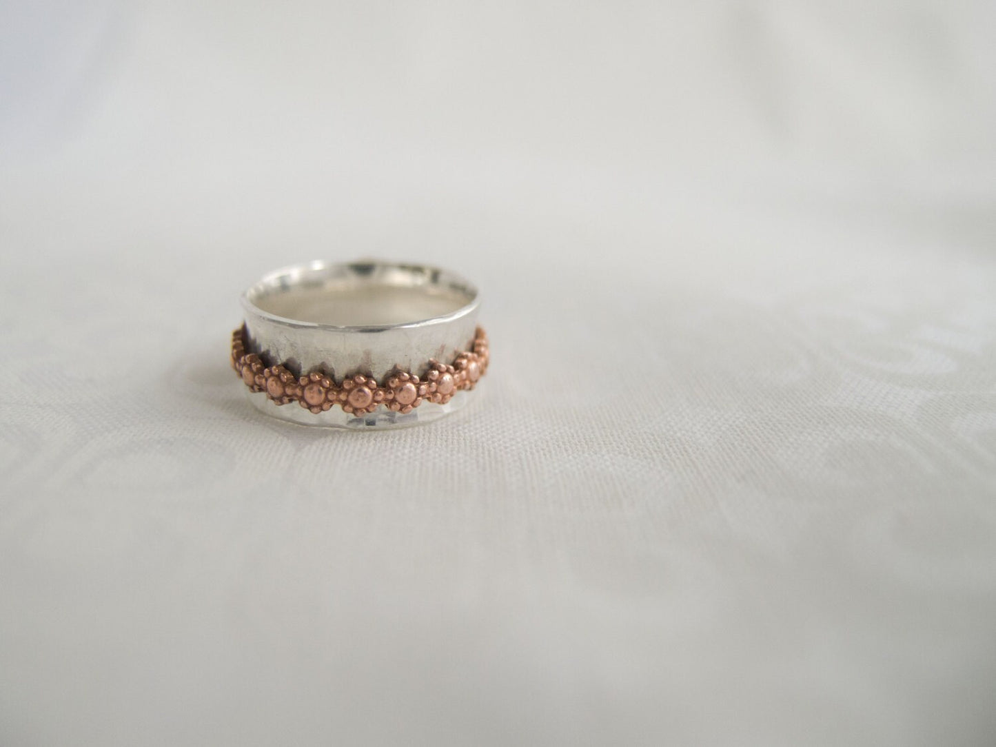 Sterling silver wide hammered ring band with a copper daisy free spinning inner fidget band.